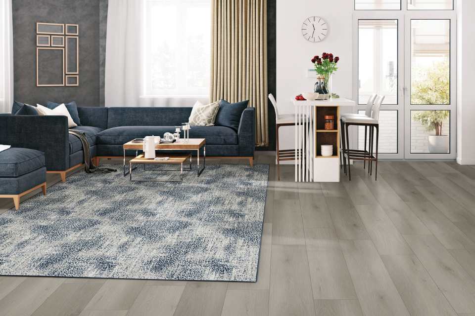 blue animal print area rug in living room with grey walls, blue couch and grey luxury vinyl plank